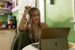 A woman with dreadlocks sitting in front of a laptop.